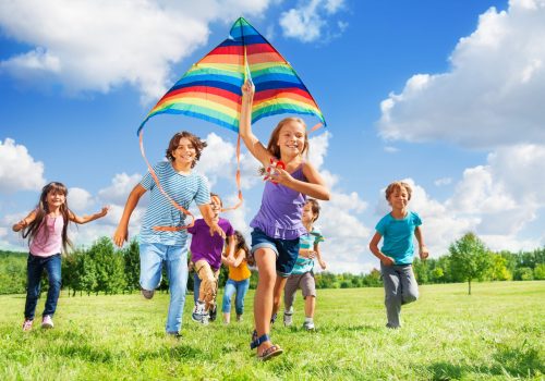 Many happy active kids boys and girls run with kite in the park